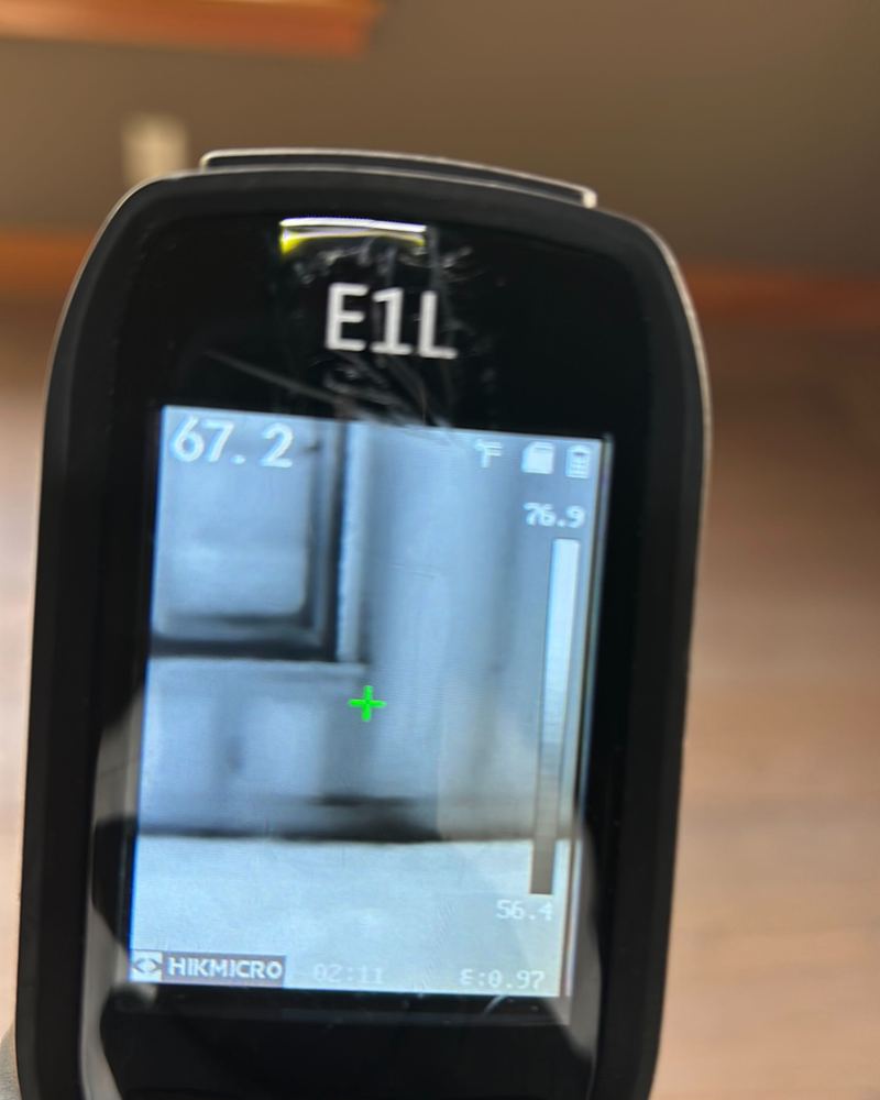 An infrared camera screen showing a cooler area on the wall.