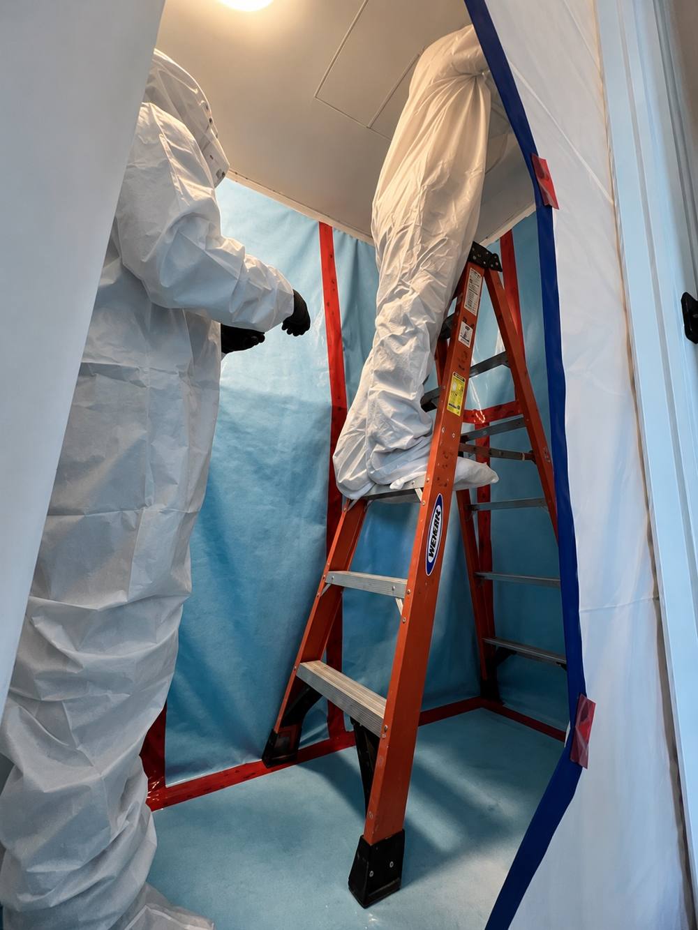 HomeCleanse technicians in protective suits working inside plastic containment during a remediation project