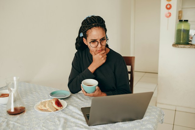Woman at her kitchen table with a cup of coffee, thinking through whether to test her home for mold Woman at her kitchen table with a cup of coffee, thinking through whether to test her home for mold